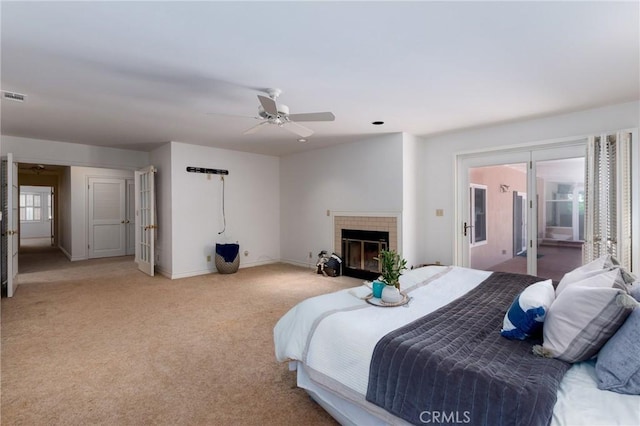 bedroom with access to outside, ceiling fan, a fireplace, and light colored carpet