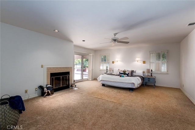 carpeted bedroom featuring access to exterior, ceiling fan, multiple windows, and a brick fireplace