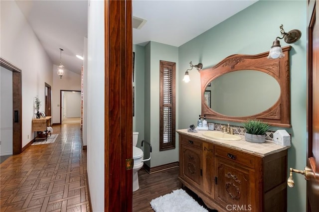 bathroom featuring parquet flooring, vanity, and toilet