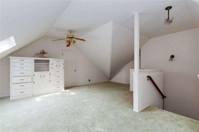 bonus room with light carpet, lofted ceiling with skylight, and ceiling fan