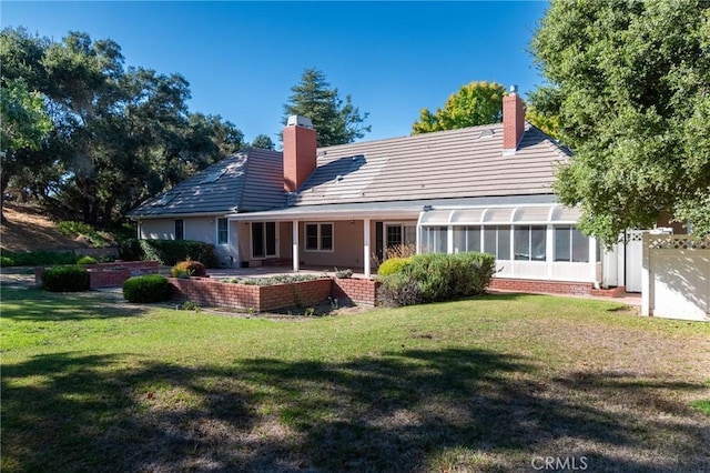 rear view of property featuring a yard, a patio area, and a sunroom