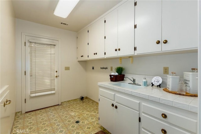 clothes washing area featuring hookup for an electric dryer, cabinets, sink, and washer hookup