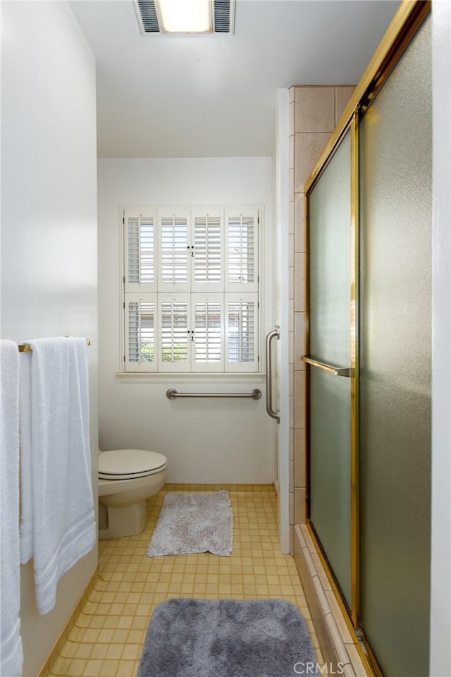 bathroom with toilet and a shower with door