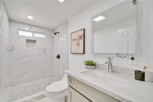 bathroom with a tile shower, vanity, and toilet