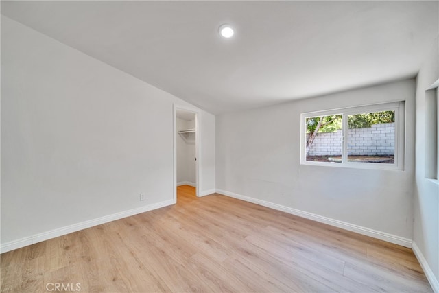 unfurnished bedroom featuring light wood-type flooring, a walk in closet, and a closet