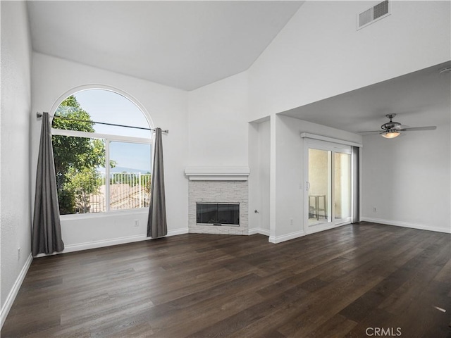 unfurnished living room featuring dark hardwood / wood-style floors, a stone fireplace, and ceiling fan