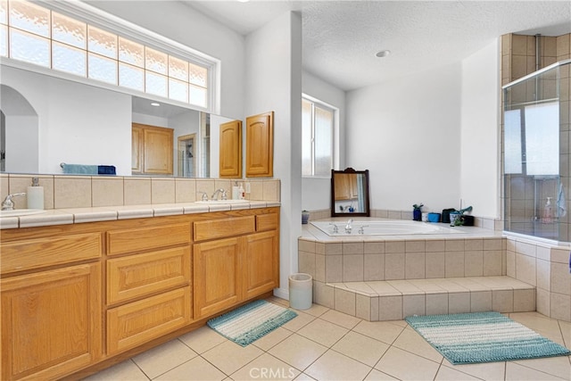 bathroom featuring vanity, plus walk in shower, tile patterned flooring, and a textured ceiling