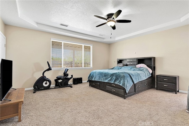 bedroom featuring ceiling fan, carpet floors, a tray ceiling, and a textured ceiling