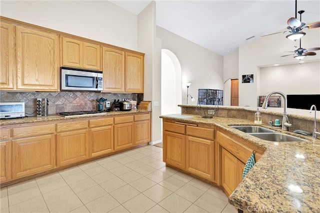 kitchen featuring appliances with stainless steel finishes, light tile patterned flooring, backsplash, ceiling fan, and sink