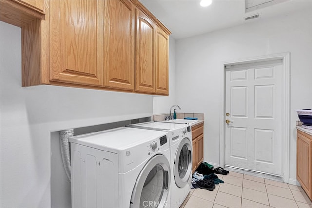 laundry room with cabinets, light tile patterned flooring, washer and dryer, and sink