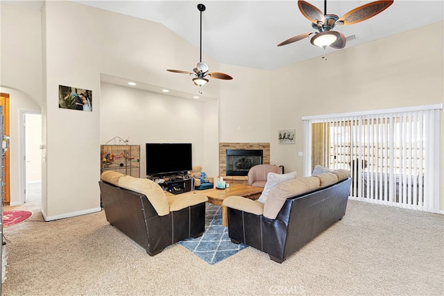 carpeted living room featuring ceiling fan, a stone fireplace, and high vaulted ceiling