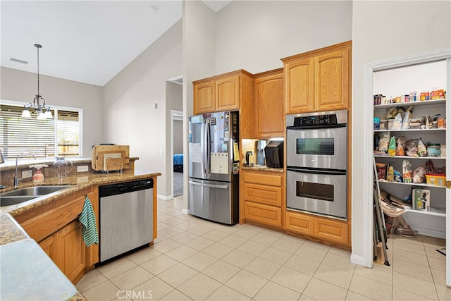 kitchen with sink, decorative light fixtures, high vaulted ceiling, stainless steel appliances, and an inviting chandelier