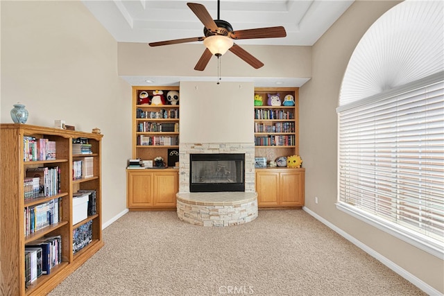 living room with light carpet, ceiling fan, a fireplace, and built in features