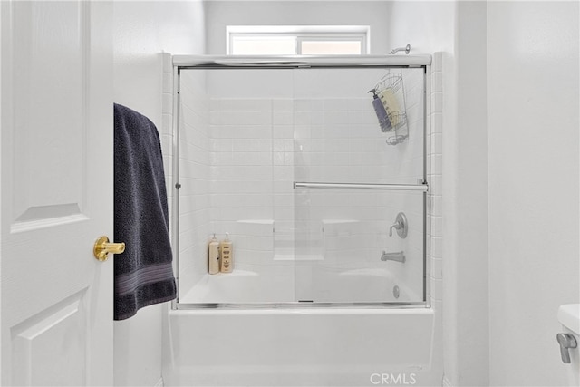 bathroom featuring bath / shower combo with glass door and toilet