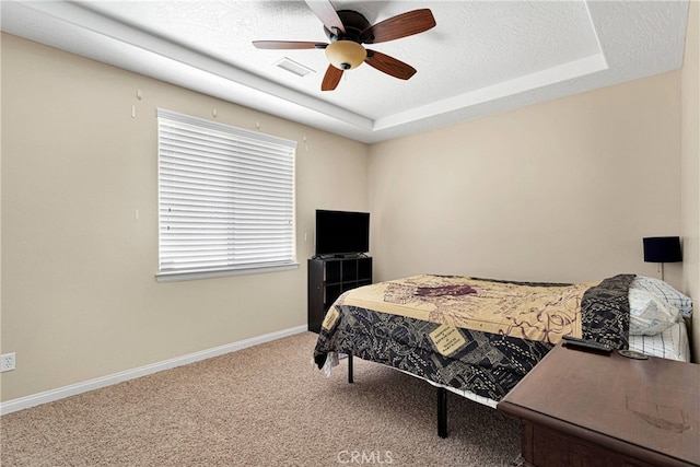 carpeted bedroom with a textured ceiling, a raised ceiling, and ceiling fan