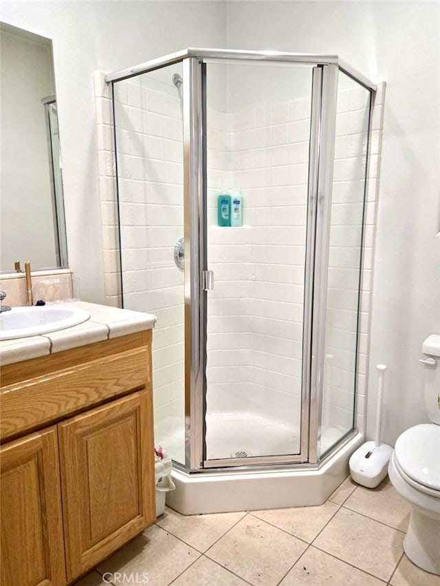 bathroom with tile patterned flooring, walk in shower, vanity, and toilet