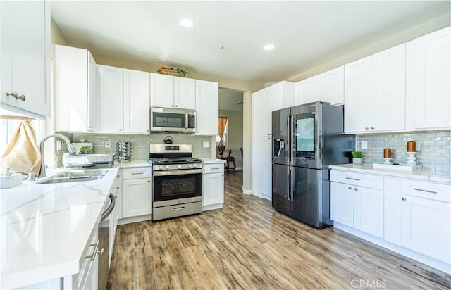 kitchen featuring white cabinetry, a sink, appliances with stainless steel finishes, and tasteful backsplash