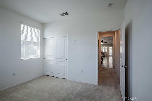 unfurnished bedroom featuring a closet, light colored carpet, and multiple windows