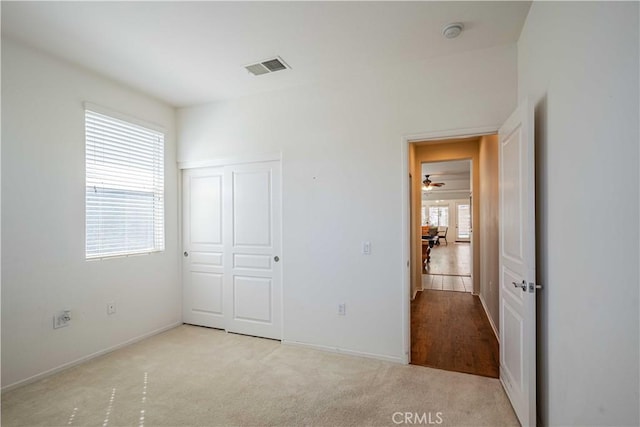 unfurnished bedroom with light colored carpet and a closet