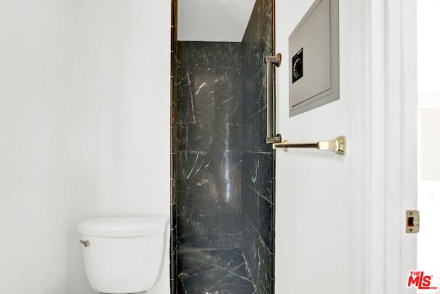 bathroom with toilet and tiled shower