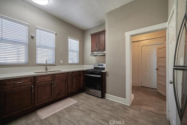 kitchen featuring dark brown cabinetry, sink, and stainless steel stove