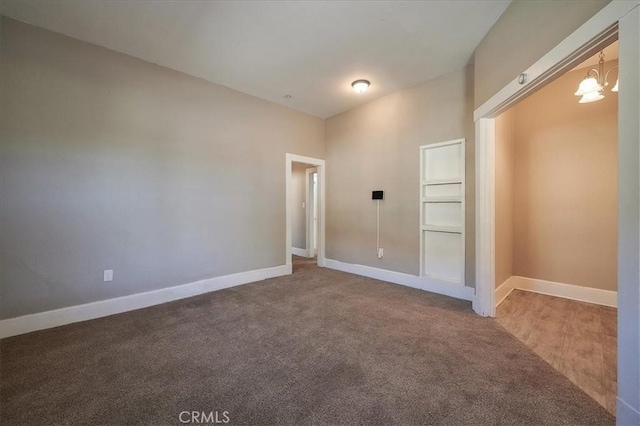 carpeted spare room featuring a notable chandelier