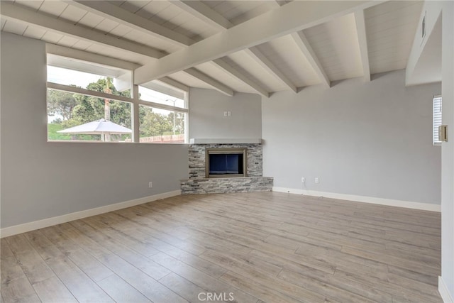 unfurnished living room featuring vaulted ceiling with beams, a stone fireplace, and light hardwood / wood-style flooring