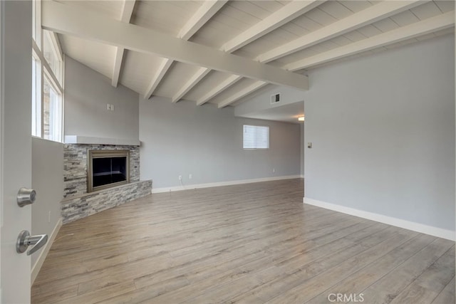 unfurnished living room featuring light hardwood / wood-style flooring, vaulted ceiling with beams, and a stone fireplace