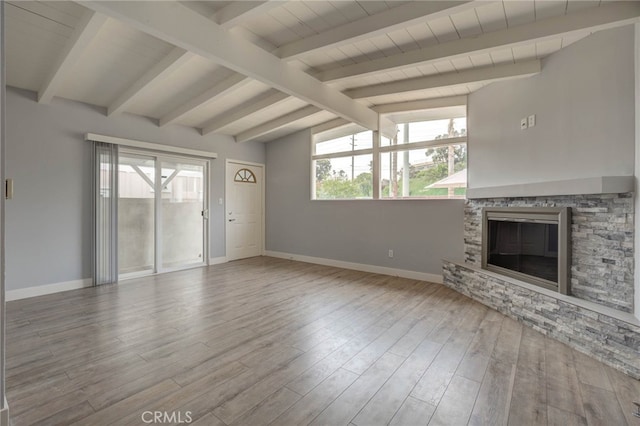 unfurnished living room with lofted ceiling with beams, a wealth of natural light, and light wood-type flooring