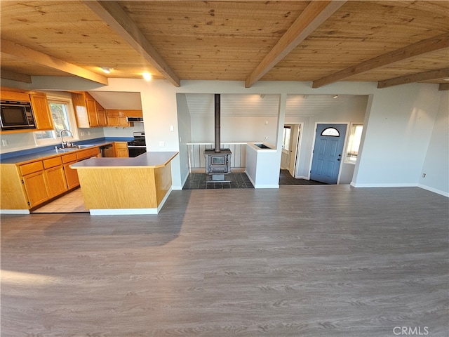 kitchen featuring wood ceiling, light wood-type flooring, a wood stove, beam ceiling, and appliances with stainless steel finishes