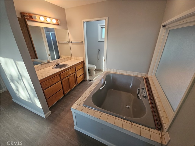 bathroom featuring vanity, hardwood / wood-style flooring, a washtub, and toilet