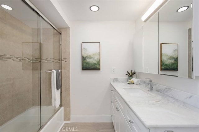 bathroom with enclosed tub / shower combo, wood-type flooring, and vanity