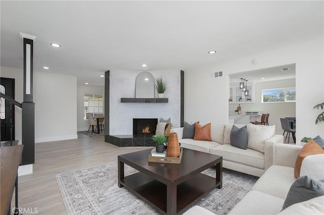 living room with light hardwood / wood-style floors and a tiled fireplace