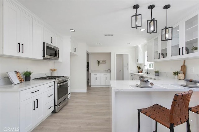 kitchen with white cabinets, appliances with stainless steel finishes, and light hardwood / wood-style flooring