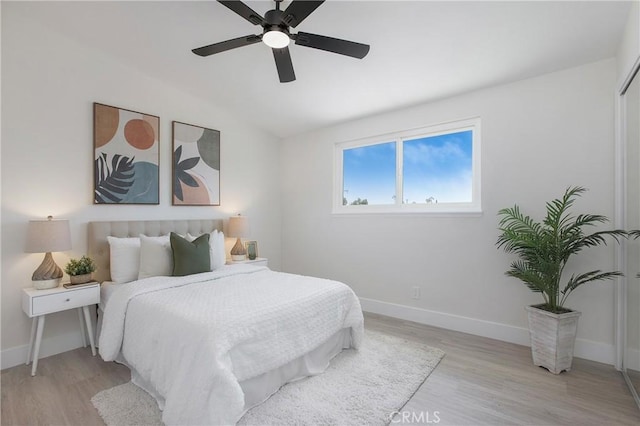 bedroom with ceiling fan, vaulted ceiling, and light wood-type flooring