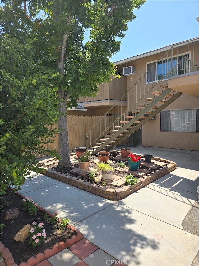 exterior space with a wall mounted air conditioner and a patio