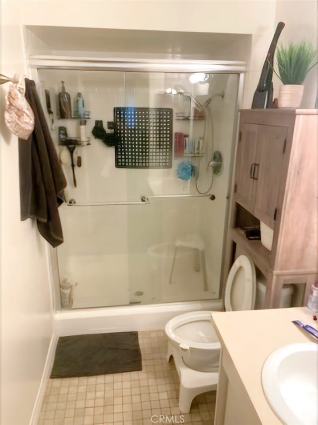 bathroom featuring vanity, a shower with shower door, toilet, and tile patterned floors