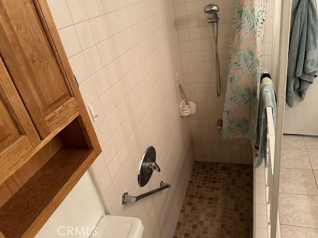 bathroom featuring curtained shower, tile patterned flooring, and toilet