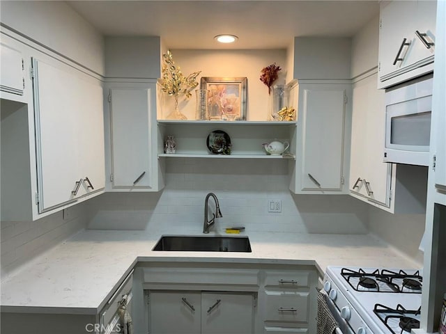 kitchen featuring white cabinets, decorative backsplash, sink, and white microwave