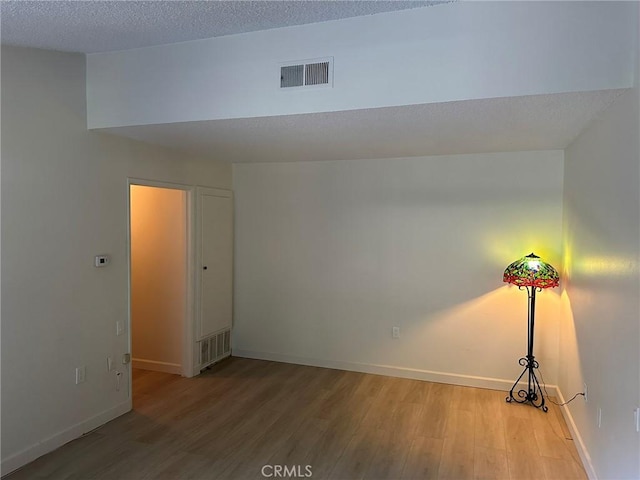 empty room featuring a textured ceiling and light hardwood / wood-style flooring