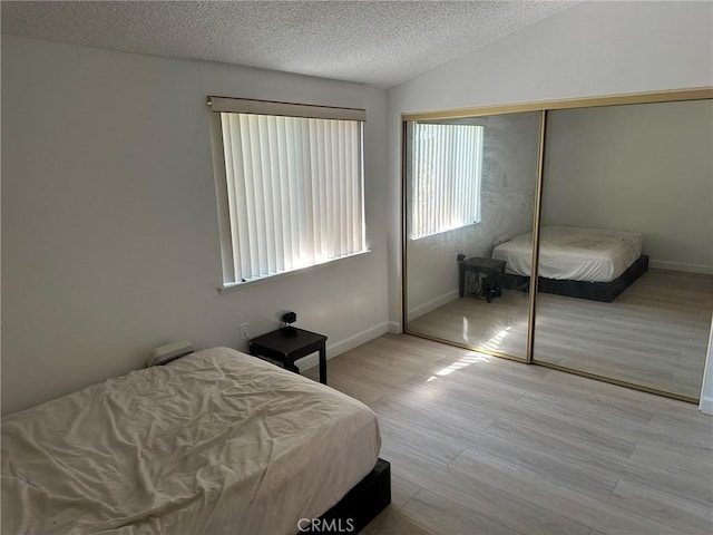 bedroom with a closet, vaulted ceiling, and light wood-type flooring