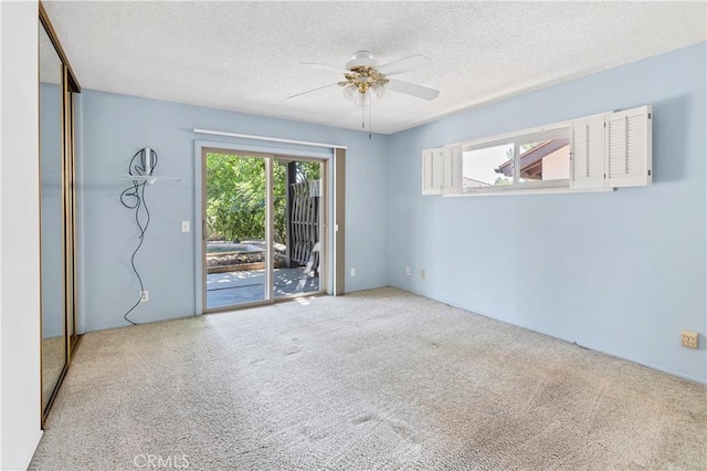 carpeted spare room with ceiling fan and a textured ceiling