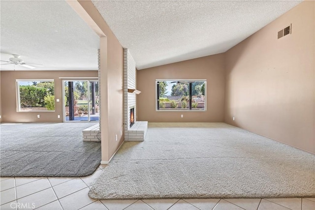 unfurnished living room featuring light tile patterned floors, a textured ceiling, a brick fireplace, and vaulted ceiling