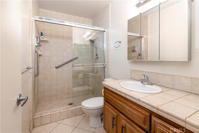 bathroom featuring tile patterned flooring, vanity, toilet, and walk in shower