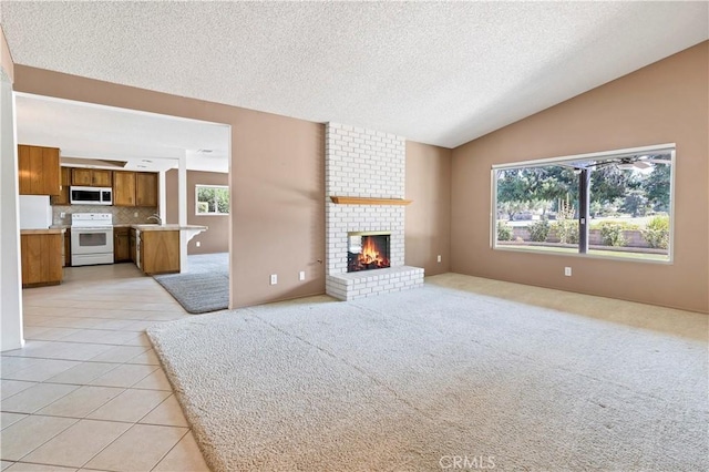 unfurnished living room with light tile patterned flooring, lofted ceiling, a textured ceiling, and a brick fireplace