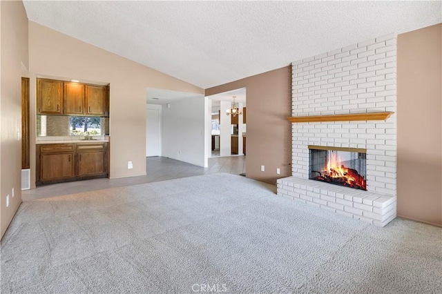 unfurnished living room with a textured ceiling, light colored carpet, a brick fireplace, and lofted ceiling