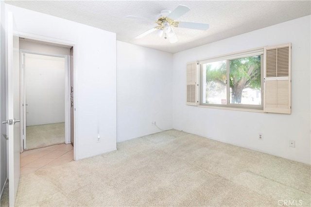 spare room featuring light carpet, a textured ceiling, and ceiling fan