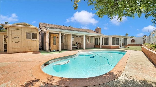 view of pool featuring a storage shed, a fenced in pool, an outdoor structure, a sunroom, and a patio