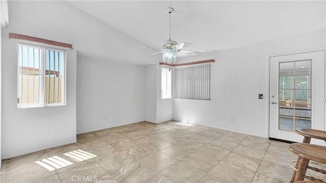 spare room with lofted ceiling, a ceiling fan, and baseboards