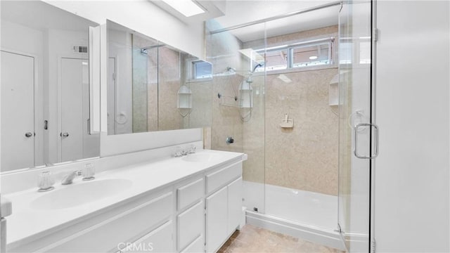 bathroom with double vanity, tile patterned floors, a stall shower, and a sink
